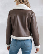 Brown faux leather shearling-trimmed zip-up biker jacket with white trim, light blue fitted jeans.