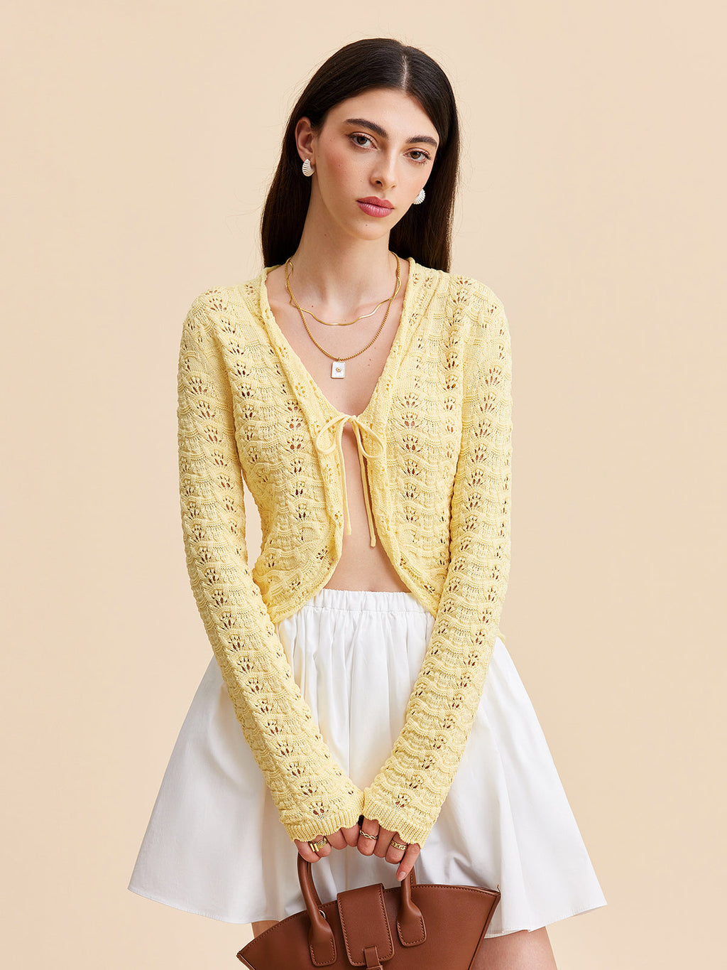 Yellow KOAD'CLO crocheted cardigan sweater with tie-front over a white top and skirt.