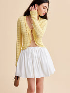 A KOAD'CLO crocheted tie-front cardigan layered over a white crop top and flared skirt.